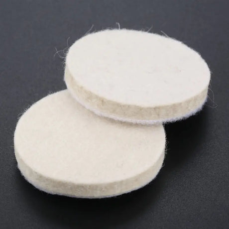 two white wool pads on a black surface
