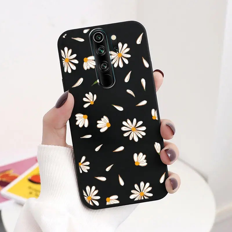 A woman holding a black phone case with white daisies on it