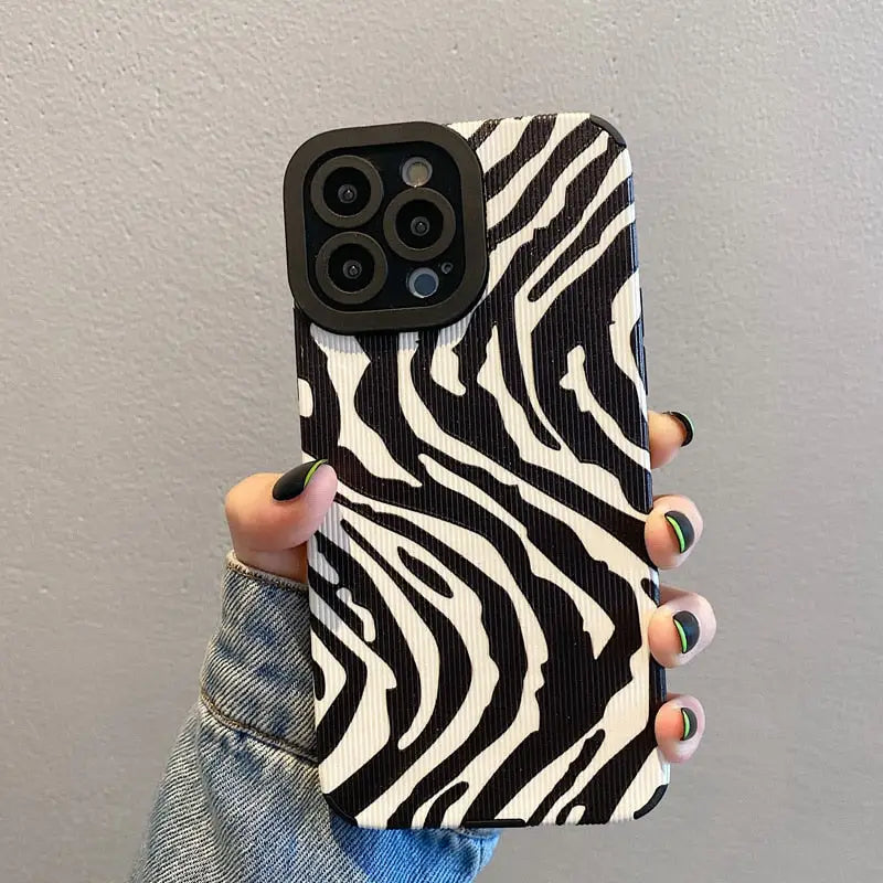 A woman holding a black and white zebra print phone case