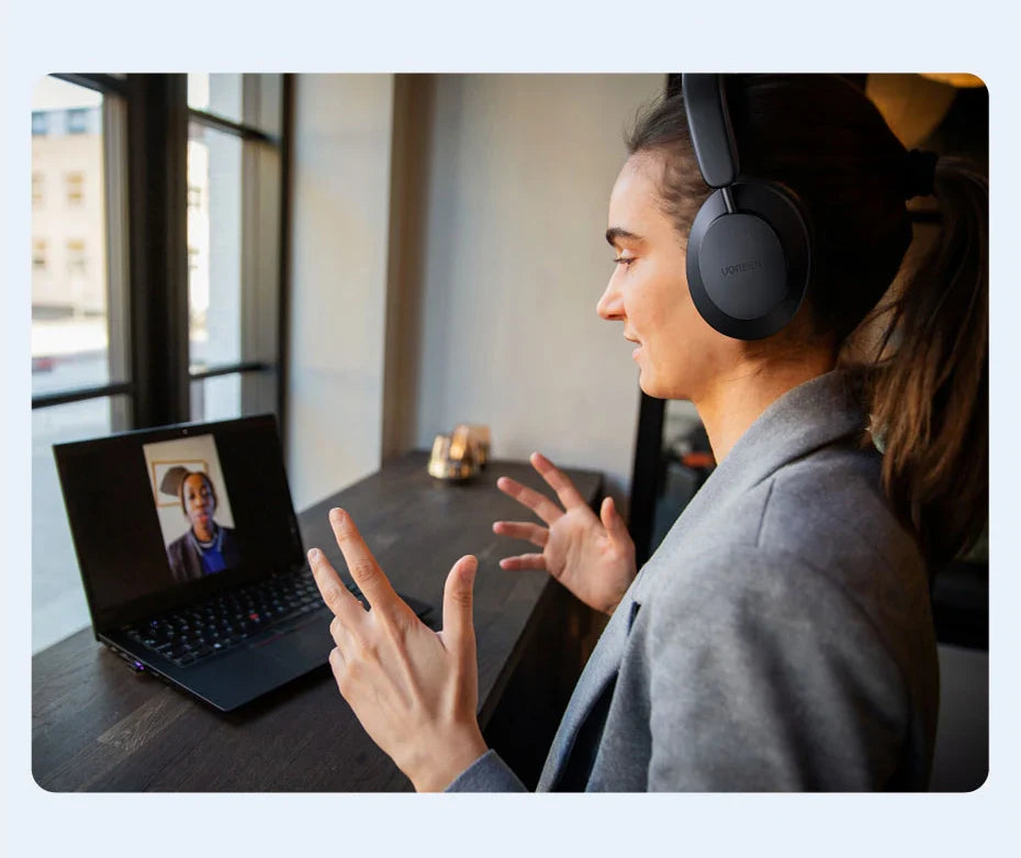 Woman wearing headphones engaged in a video call on a laptop.