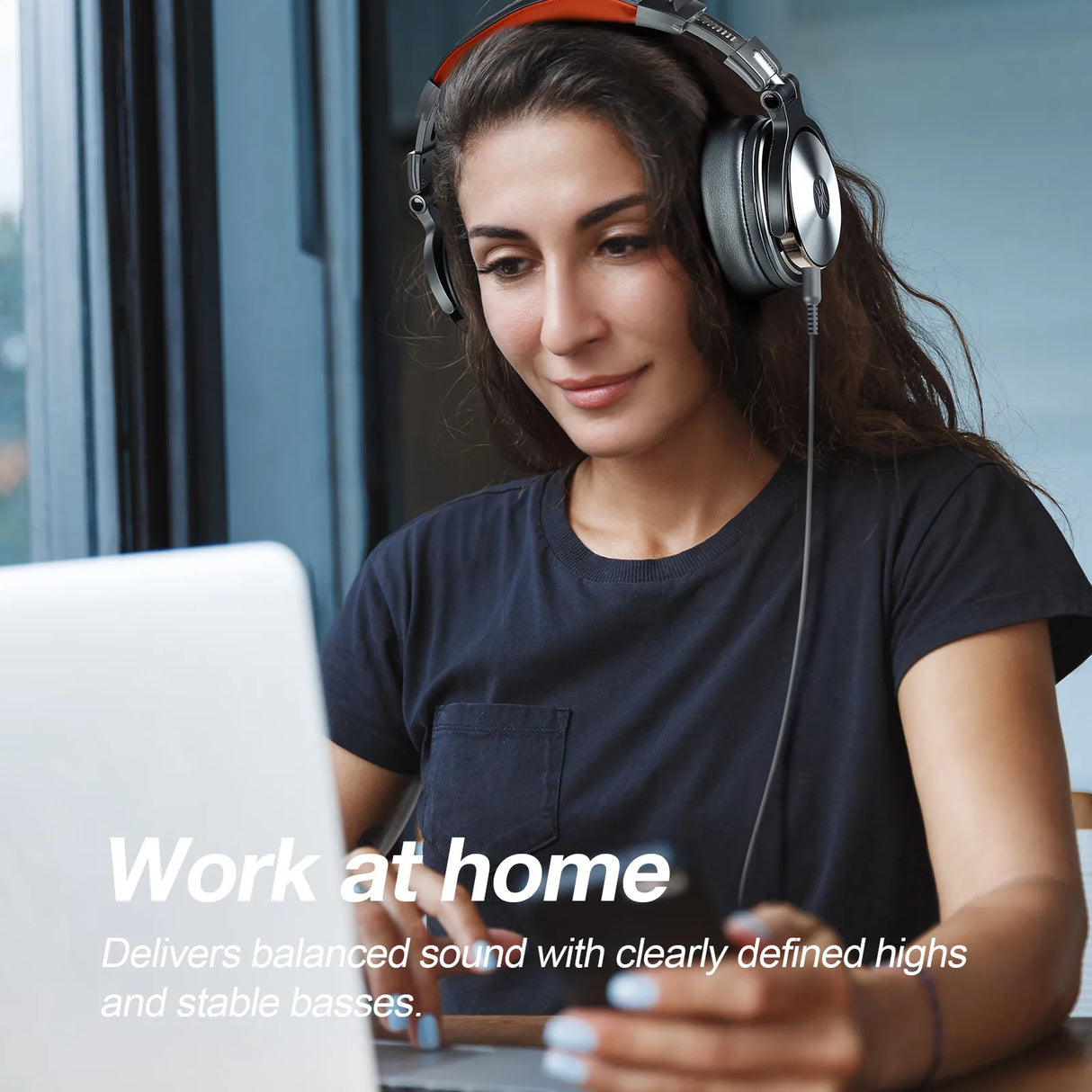 Woman wearing headphones while working on a laptop.