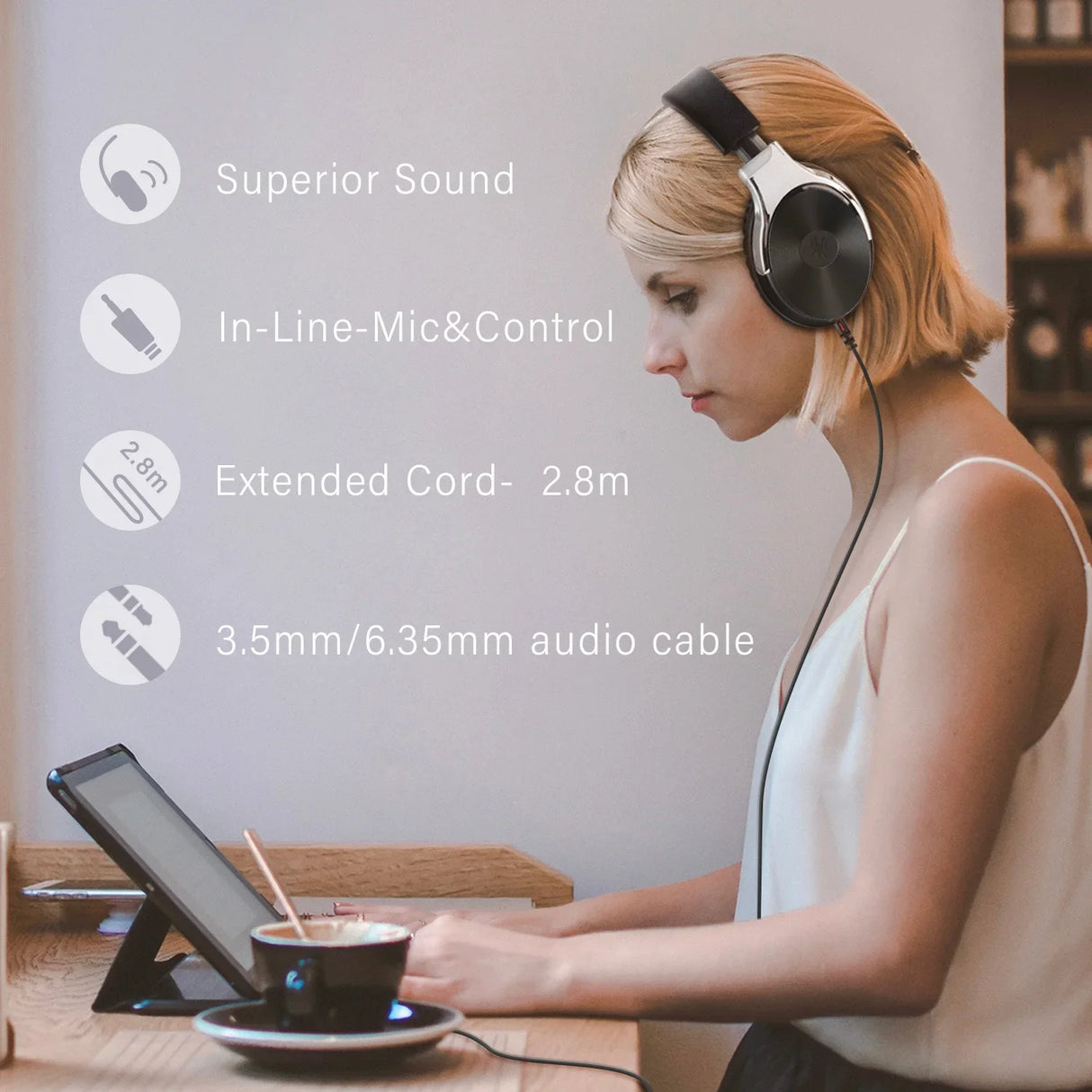 Woman wearing headphones while using a tablet device at a table with a coffee cup.