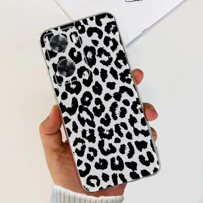 a woman holding a phone case with a black and white leopard print