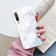a woman holding a book and a white marble phone case