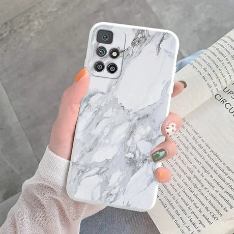 a woman holding a white marble phone case