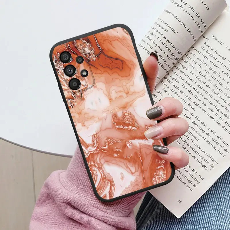 someone holding a book and a phone case with a marble design