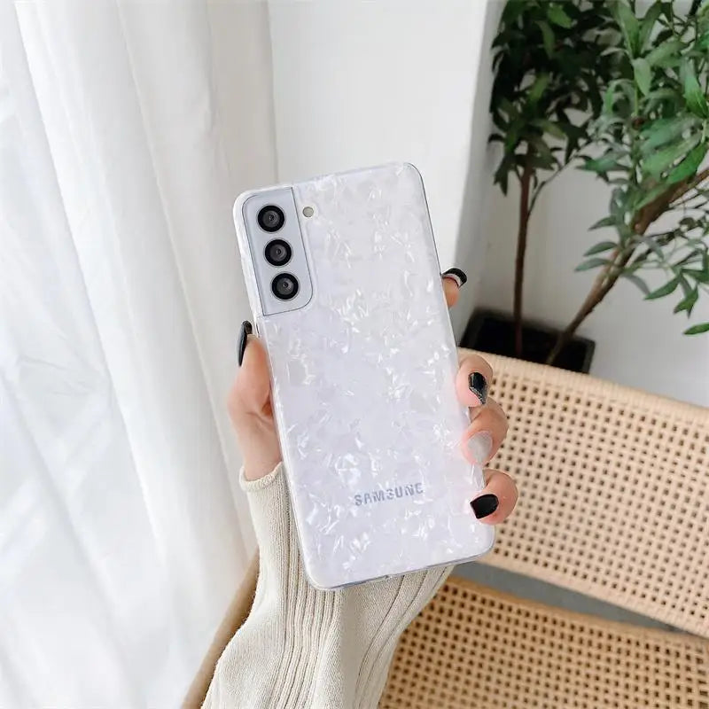 a woman holding a white phone case with a white flower design