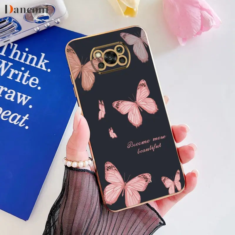 a woman holding a phone case with pink butterflies on it