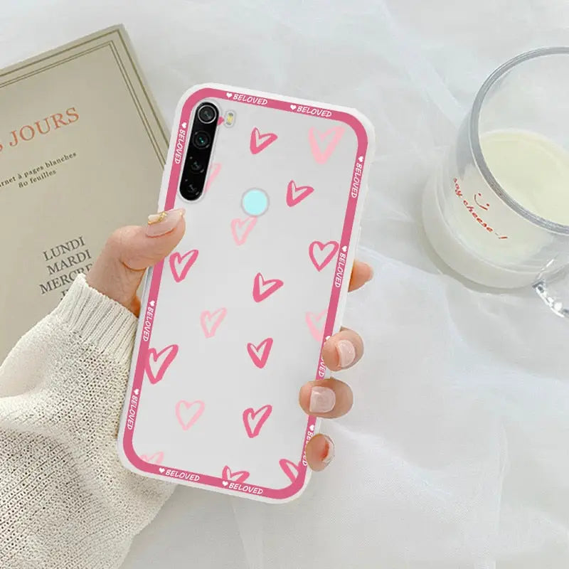 a woman holding a pink phone case with hearts on it