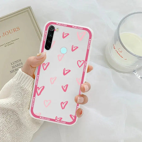 a woman holding a pink phone case with hearts on it