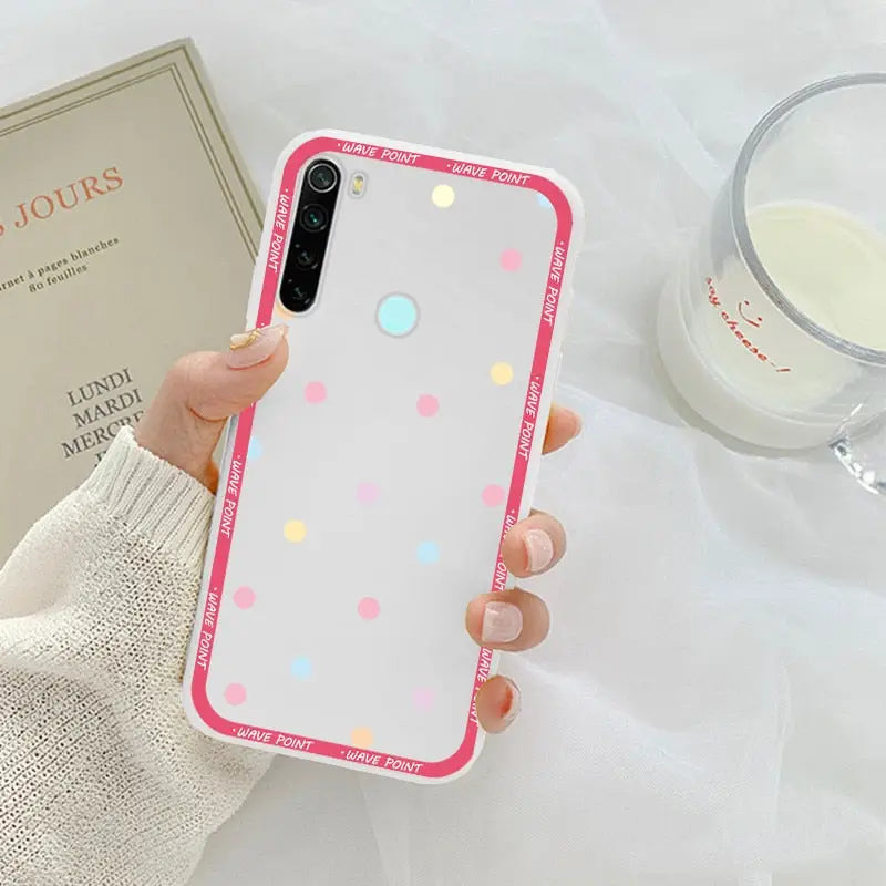 a woman holding a pink and white polka dot phone case