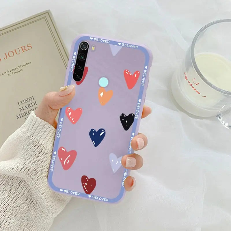a woman holding a phone case with hearts on it