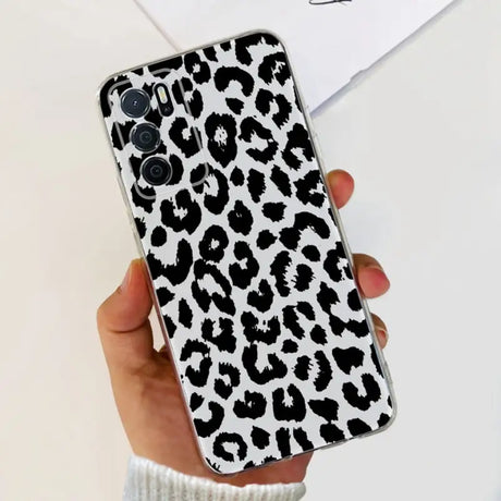 a woman holding a phone case with a black and white leopard print