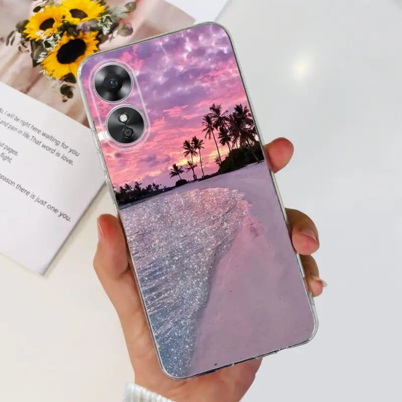 a woman holding a phone case with a sunset in the background