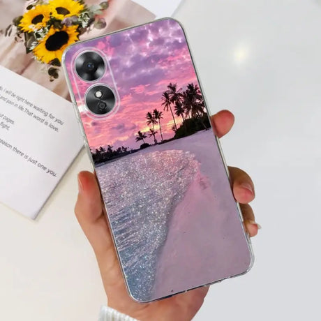 a woman holding a phone case with a sunset in the background