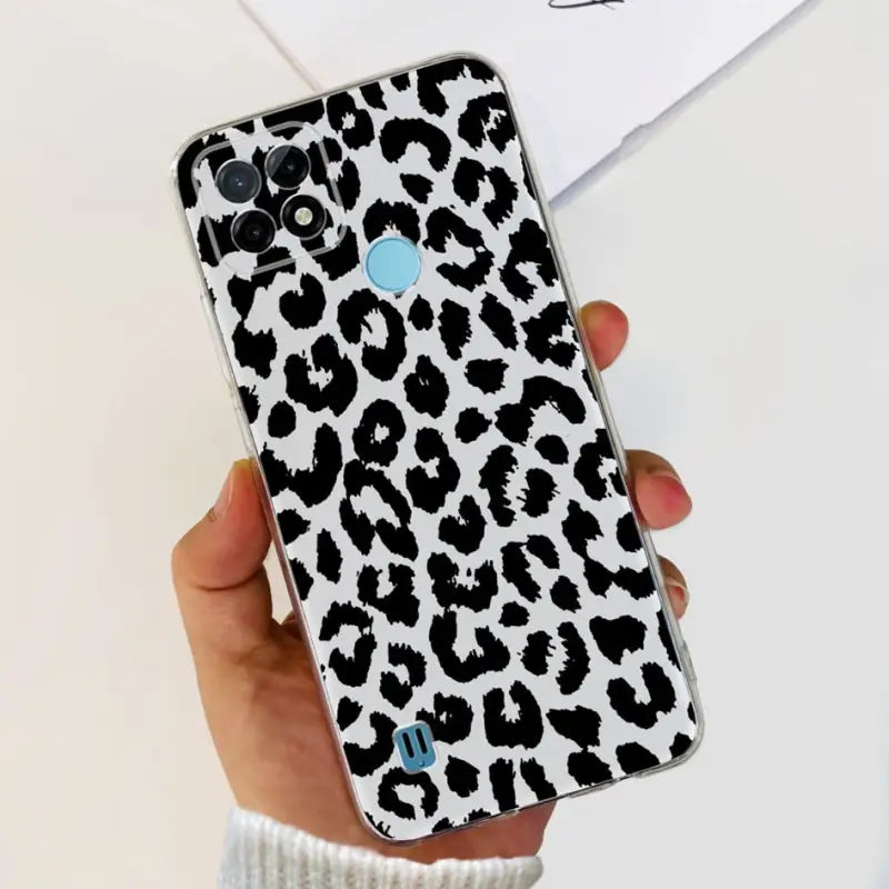 a woman holding a phone case with a black and white leopard print