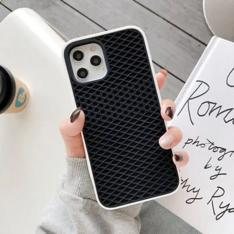 a woman holding a phone case with a black diamond pattern