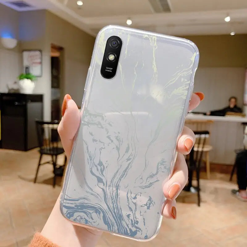 a woman holding up a phone case with a marble pattern