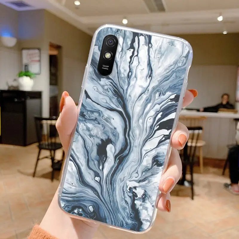 a woman holding up a phone case with a marble pattern