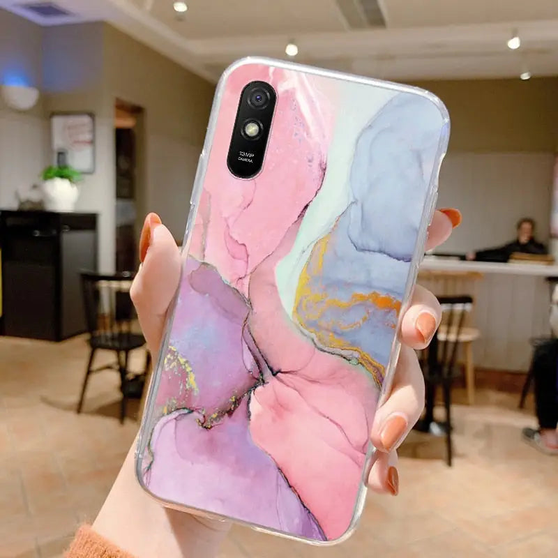 a woman holding up a phone case with a marble pattern