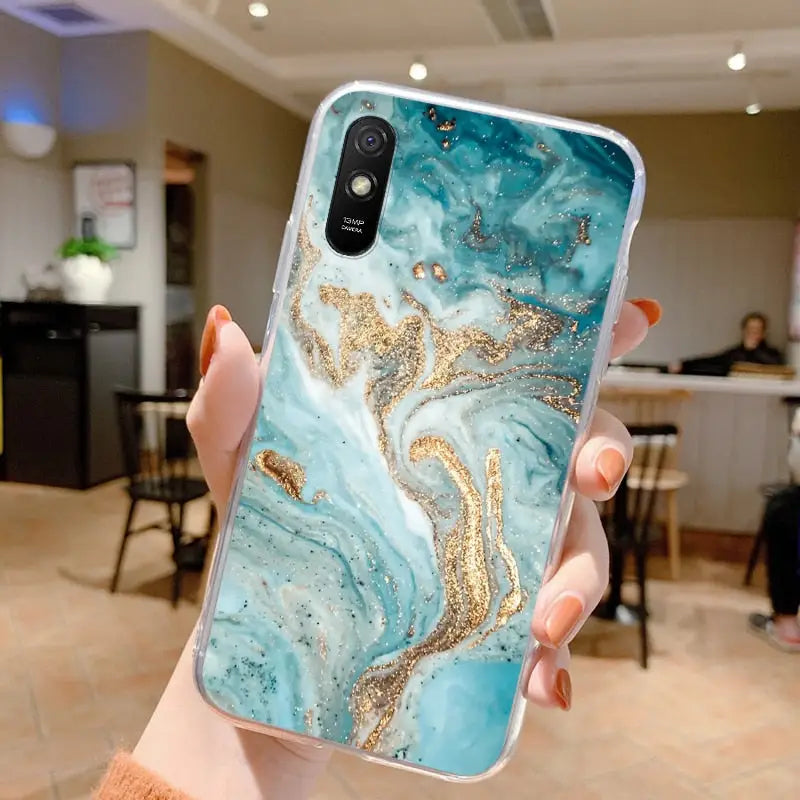 a woman holding up a phone case with a gold glitter on it