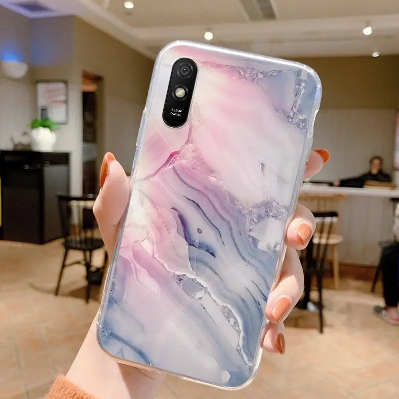 a woman holding up a phone case with a marble pattern