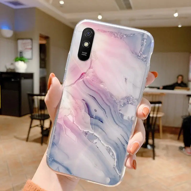 a woman holding up a phone case with a marble pattern