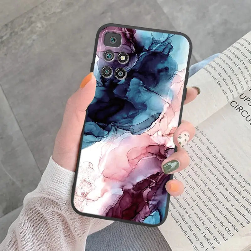 a woman holding a phone case with a watercolor painting on it