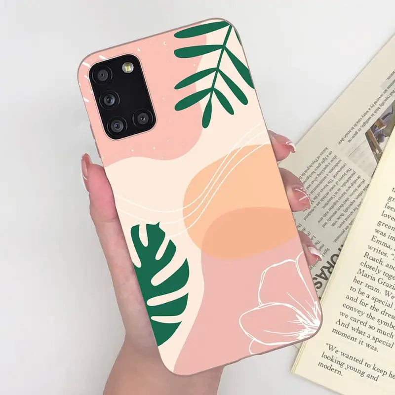 a woman holding a phone case with a pink and green leaf pattern