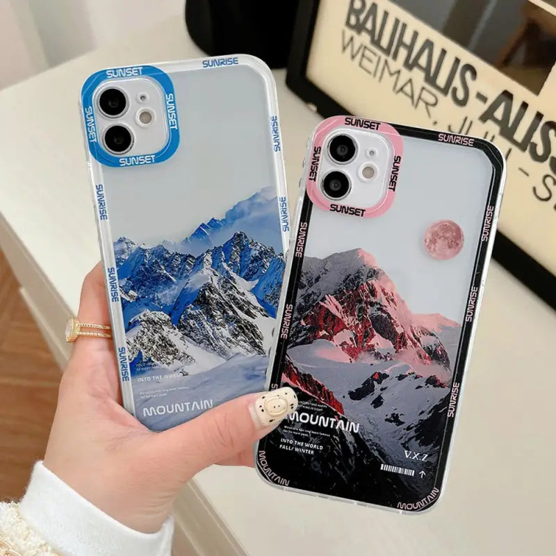 a woman holding a phone case with mountains in the background