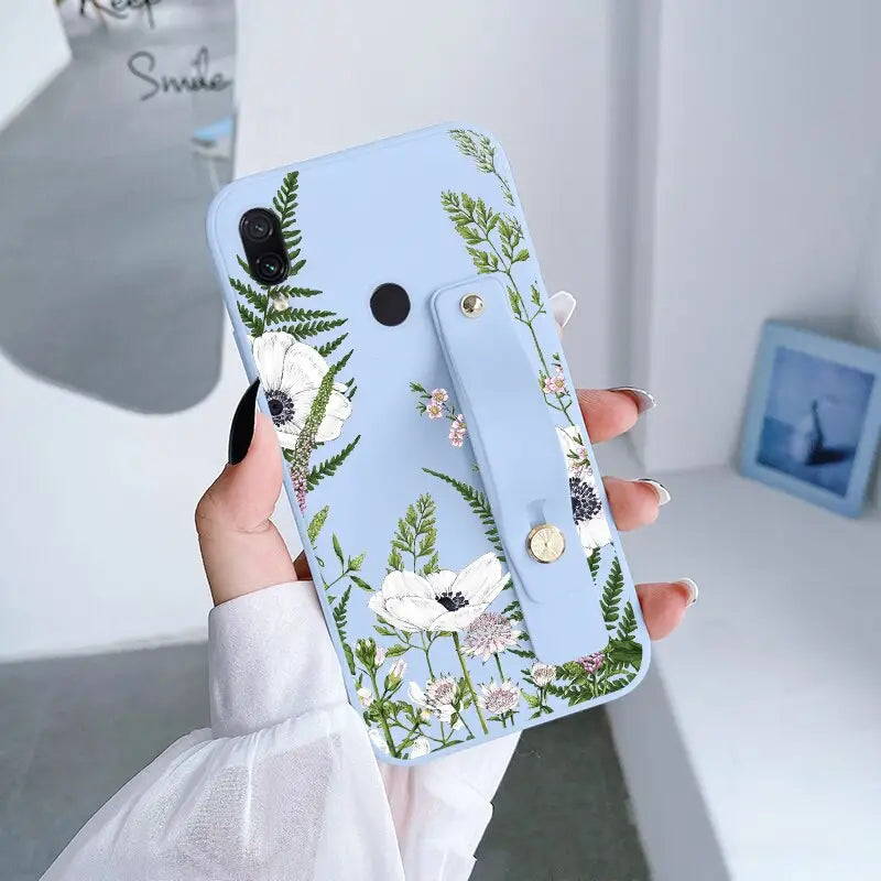 a woman holding a phone case with flowers on it