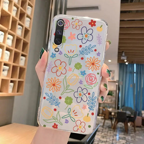 a woman holding up a phone case with flowers on it