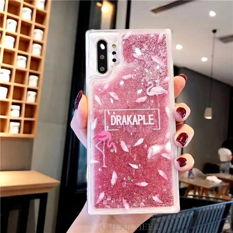 a woman holding a pink glitter phone case