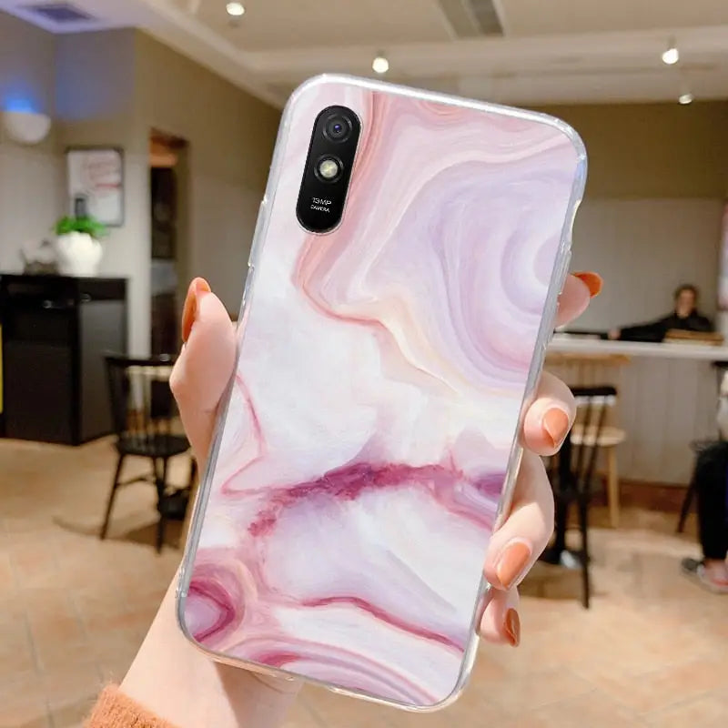 a woman holding up a pink marble phone case