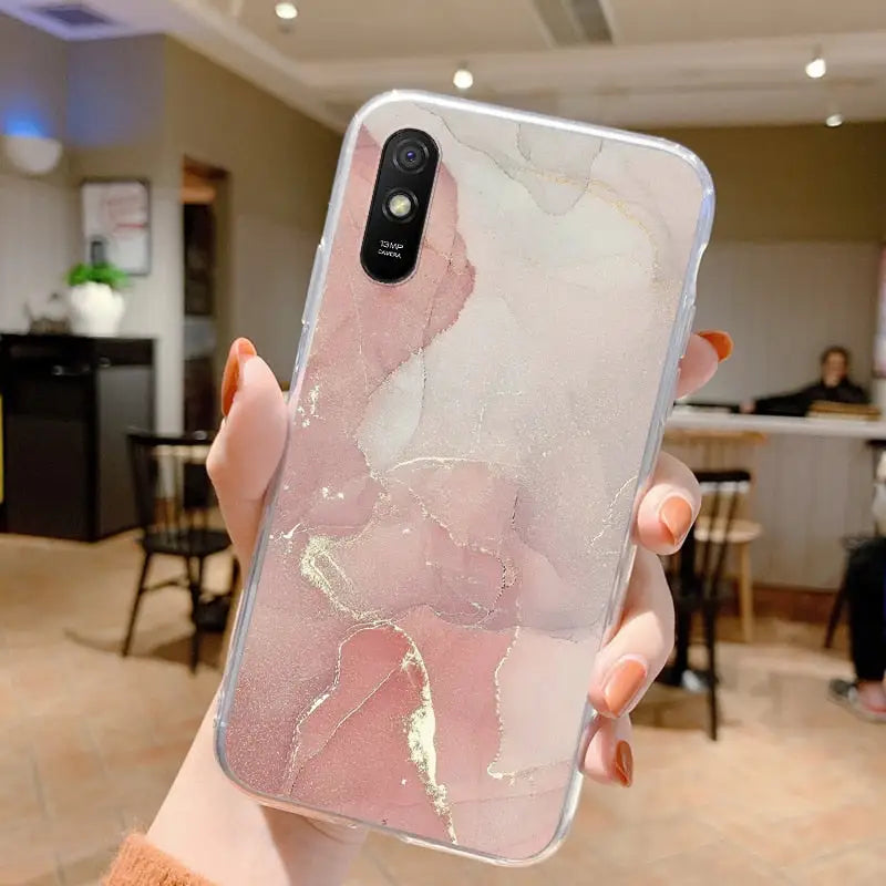 a woman holding a phone case with a pink marble pattern