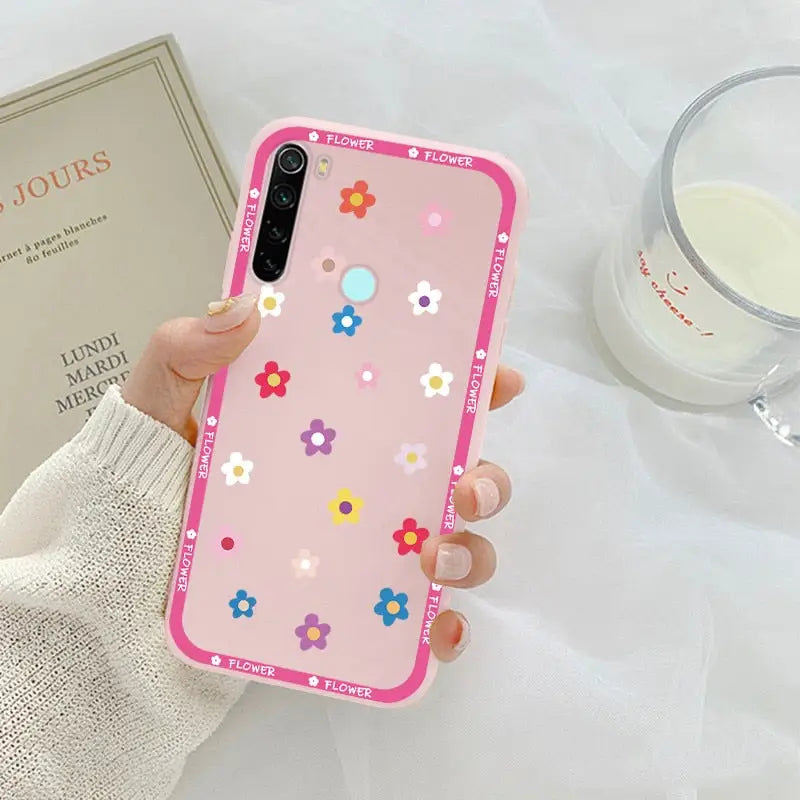 a woman holding a pink phone case with flowers on it
