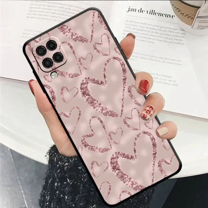 a woman holding a pink glitter phone case