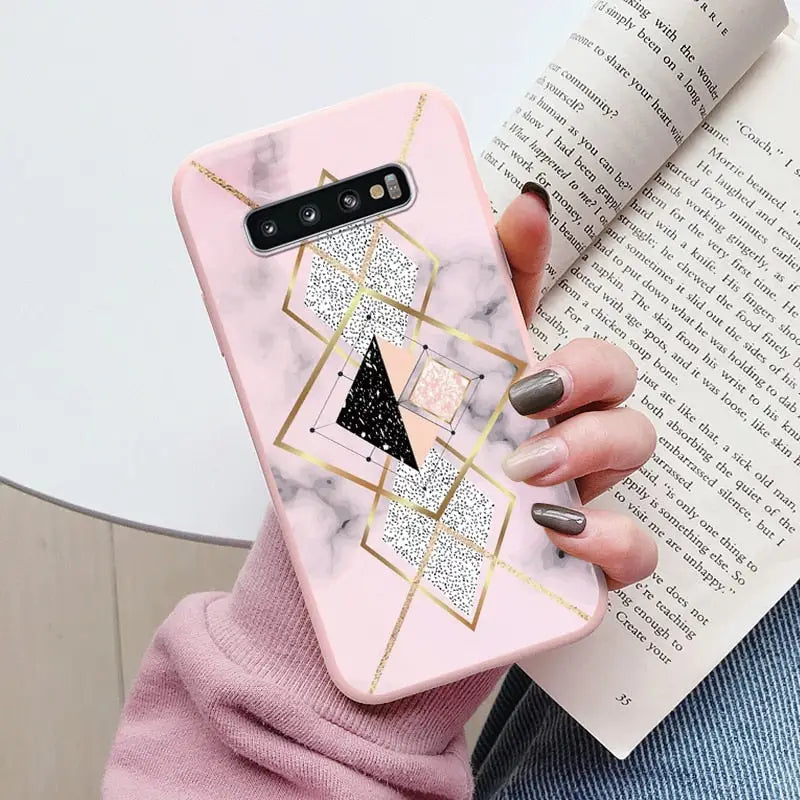 a woman holding a pink marble phone case with gold geometric design