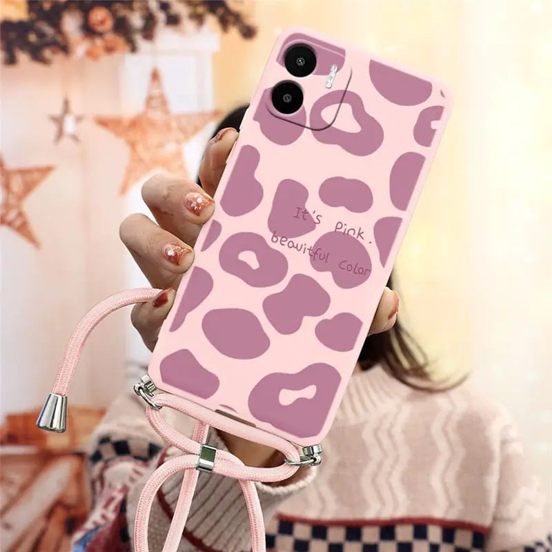 a woman holding a pink phone case with a pink leopard print