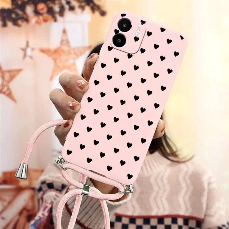 a woman holding a pink phone case with black hearts on it
