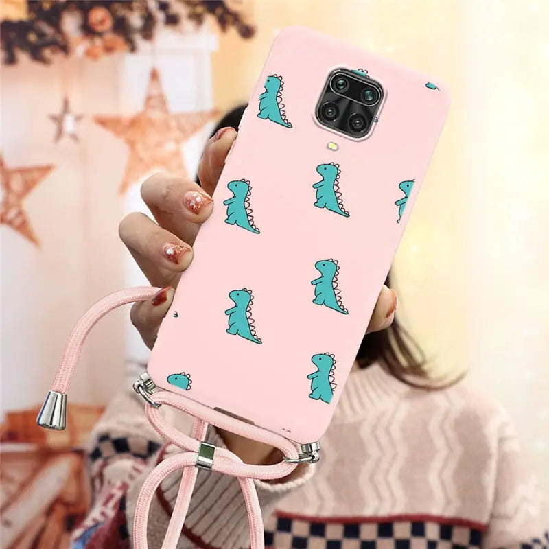 a woman holding a pink phone case with a green dinosaur print