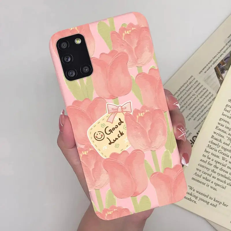 a woman holding a pink phone case with a floral pattern