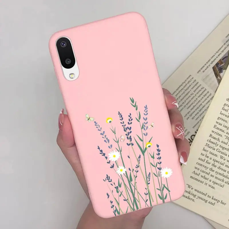 a woman holding a pink phone case with flowers on it