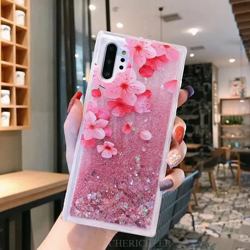 a woman holding a pink phone case with flowers on it