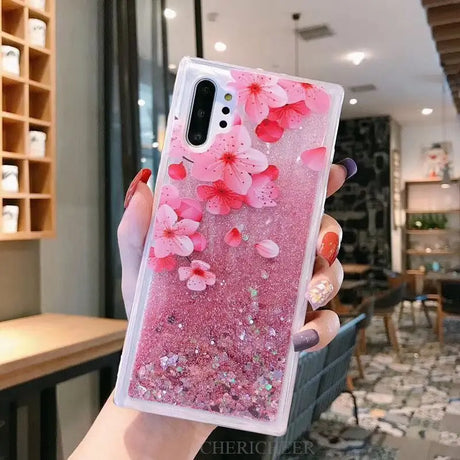 a woman holding a pink phone case with flowers on it