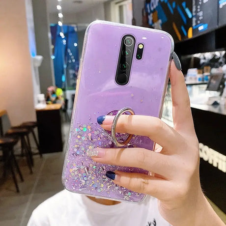 a woman holding a purple phone case with glitter