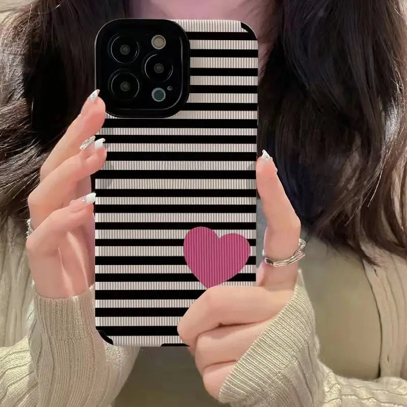 a woman holding up a phone case with a heart
