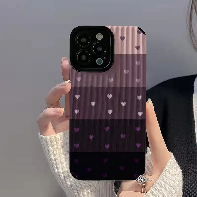 a woman holding up a phone case with hearts on it