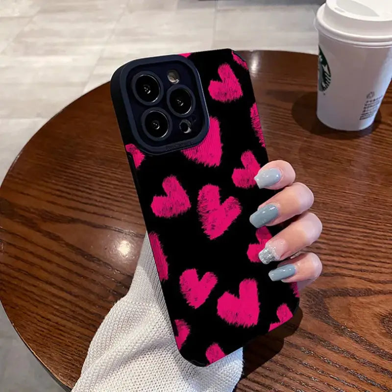 A woman holding a phone case with pink hearts on it