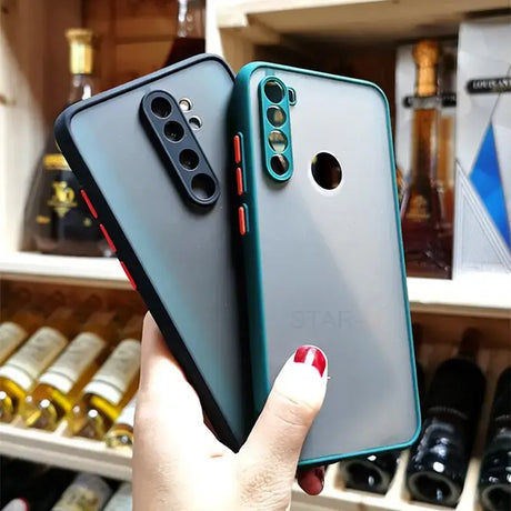 a woman holding up a phone case in front of a wine rack